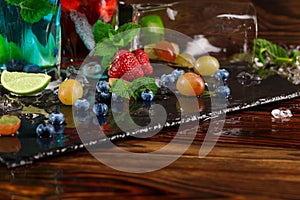 Close-up of beautiful ripe berries with mint. Bright sweet grapes, bilberries and strawberries on the black desk. Copy space.