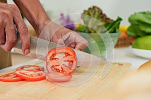 Close-up beautiful round red tomato on cutting board, Man cooking in kitchen during holidays who doesn't want go out eat,