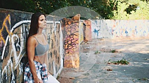 Close up. Beautiful, sexy, fitness girl is angry on graffiti background. Side view. Slowmo. Slow. motion. Copy space. 4K