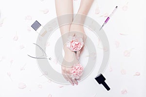Close-up beautiful sophisticated woman hands with pink flowers on white background. Concept organic manicure hand care