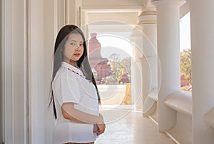 Close up of beautiful thai woman in a white traditional thai dress is standing in white temple with smilingly face photo
