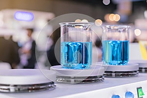 Close up of beautiful vortex blue colorful chemistry liquid in beaker laboratory flask on magnetic stirrer or mixer machine for photo