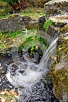 A close up of a beautiful waterful , the water creates a ripple effect as it splashes into the pond below.