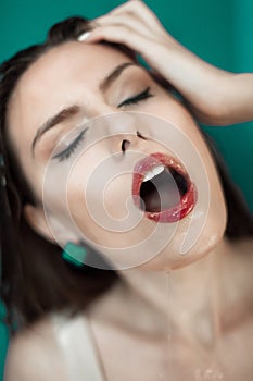 Close-up of beautiful wet woman face with water drop. On green background