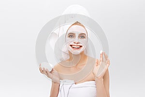 Close-up beautiful woman applying moisturizer cosmetic cream on face on light background.