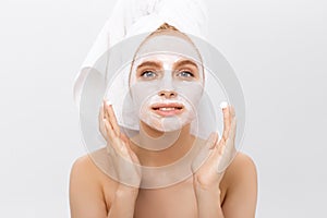 Close-up beautiful woman applying moisturizer cosmetic cream on face on light background.