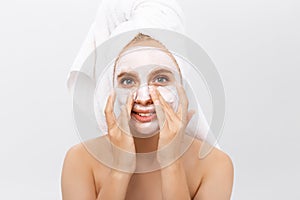 Close-up beautiful woman applying moisturizer cosmetic cream on face on light background.