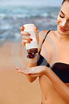 Close up beautiful woman in bikini applying sun cream on hands