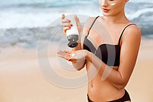 Close up beautiful woman in bikini applying sun cream on hands. Sun protection. Skin care. Girl using sunscreen to skin