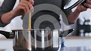 Close up of beautiful woman cooking healthy food in casserole in the kitchen at home.