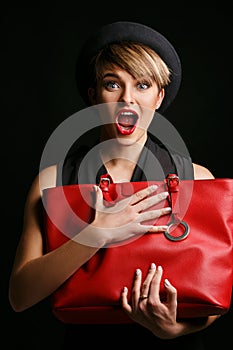 Close up of a beautiful woman with a good sense of humor , holding her fancy red bag.