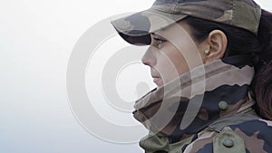 Close-up, beautiful woman in military camouflage drinks hot tea from metal mug on river background in fog on an autumn