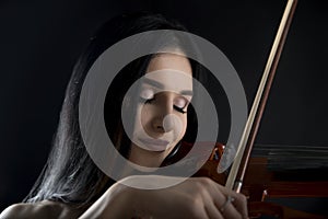 Close up of beautiful woman playing on electric violin on blac