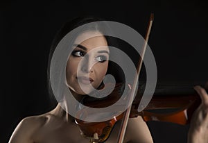 Close up of beautiful woman playing on electric violin on black