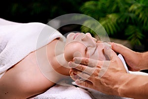 Close-up of a beautiful woman receiving a soothing head massage.