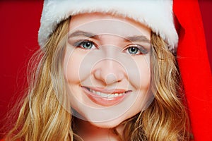 close up. a beautiful woman in a Santa Claus hat on a red background.