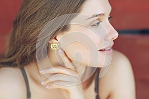 Close-up of a beautiful woman in shiny gold earrings. Portrait of a young woman in costume jewelry.