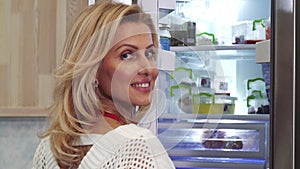 Close up of a beautiful woman smiling looking in the fridge