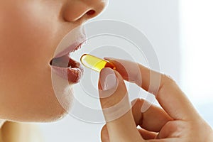 Close Up Of Beautiful Woman Taking Fish Oil Capsule In Mouth