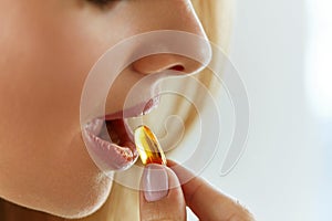 Close Up Of Beautiful Woman Taking Fish Oil Capsule In Mouth