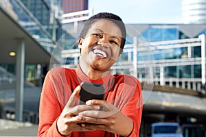 Close up beautiful young african american woman laughing with cellphone in city