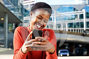 Close up beautiful young african american woman smiling and looking at cellphone