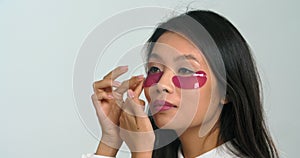 Close-up beautiful young asian ethnic woman korean teen girl applying moisturizing patches on under eyes area, feeling
