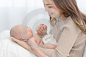 Close up beautiful young asian mother holding her newborn one month baby sleep on her arms. Healthcare and medical love asia woman