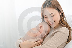 Close up beautiful young asian mother holding her newborn one month baby sleep on her arms. Healthcare and medical love asia woman