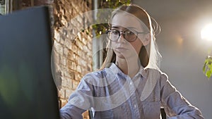Close-up. Beautiful young business woman wearing glasses is working using modern computer. Confident female employee