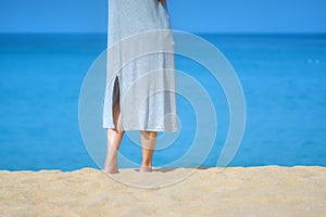 Close up beautiful young female feet barefoot walking on sand beach with sea and sky background. Morning outdoors exercise in a su