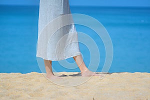 Close up beautiful young female feet barefoot walking on sand beach with sea and sky background. Morning outdoors exercise in a su