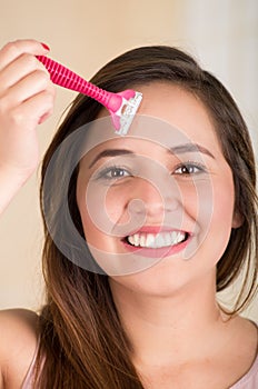 Close up of a beautiful young funny woman with an shaver on her face