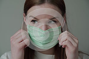 Close up of a beautiful young girl with long red hair in a medical mask. Orvi, coronovirus, acute respiratory infections. photo