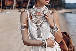 Close up of beautiful young stylish boho woman walking on the beach at sunset