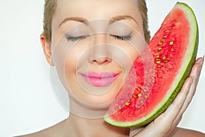 Close-up, beautiful young woman holding a watermelon face, eyes closed and gracious smile.