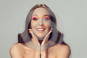 Close up of beautiful young woman with long healthy curly hair and bright make up isolated on grey studio backgroud