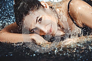 Close up of beautiful young woman lying in the water.