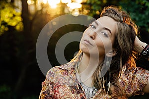Close up Beautiful young woman wearing bohostyle clothes posing in the rays of the evening sun, sunset. Boho style photo