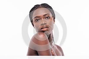 Close up beauty portrait of a african beautiful half naked woman applying face cream and looking away isolated over white