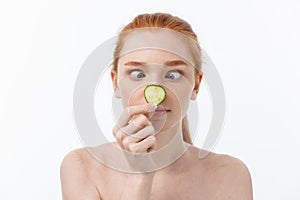 Close up beauty portrait of a smiling beautiful half naked woman holding cucumber slices at her face isolated over white