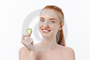 Close up beauty portrait of a smiling beautiful half naked woman holding cucumber slices at her face isolated over white