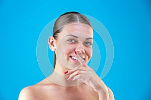 Close up Beauty portrait of young woman brunette smiling and touching her face on blue background. Perfect Fresh Skin