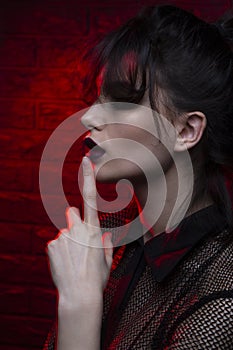 Close up beauty profile portrait of girl with dark makeup in red neon colorful studio light background.