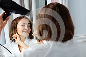 Close-up beauty woman in housecoat holding hairdryer dry hair photo