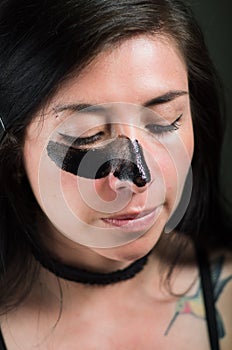 Close up of a beauty young woman aplying a black mask to clean the skin photo
