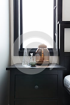 Close up of bedside table with ornaments and bright window behind