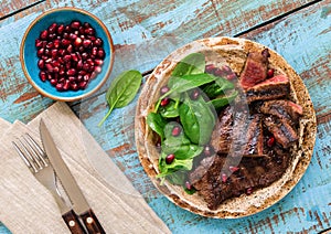Close up beef steak grilled with spinach leaves and pomegranate