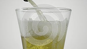 Close-up of beer being poured into clear glass. Action. Beer is poured into transparent glass on white isolated