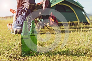 Close up of beer bottle in meadow while camping at outdoors. Holiday and Vacation concept. Adventure and outdoors theme.